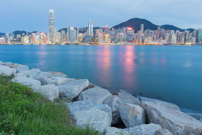 Modern skyscrapers at victoria harbour against cloudy sky