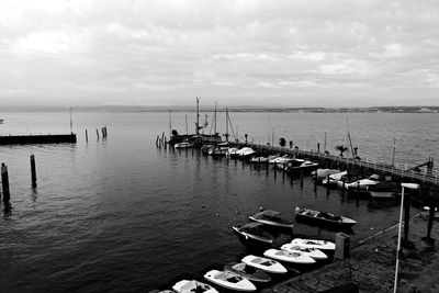 Sailboats moored in sea against sky