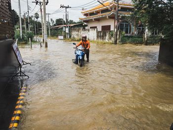 Men in canal amidst buildings