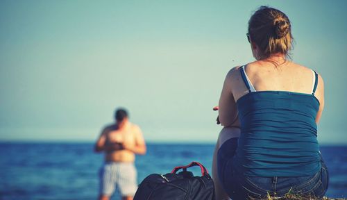 Rear view of woman with man standing against sky