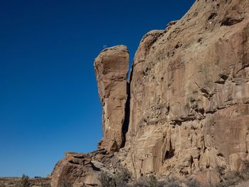 Low angle view of rock formation against clear blue sky