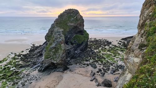 Rock formation on beach against sky during sunset