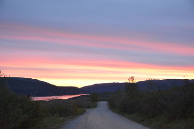 Road amidst trees against sky during sunset