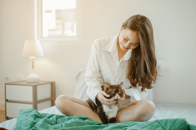 Young woman with cat on bed