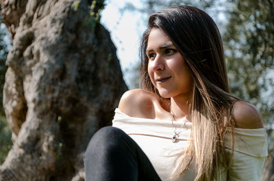 Portrait of young woman looking at tree