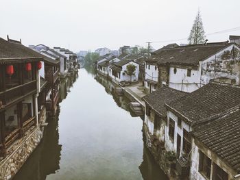 Canal amidst houses in town against sky