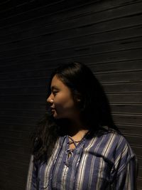 Young woman standing against shutter at night