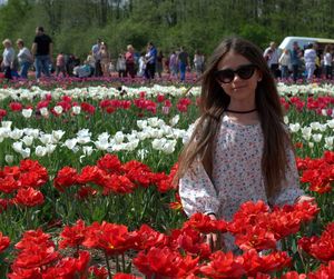 Woman wearing sunglasses standing by flower plants