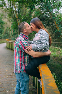 Male looking to pregnant woman holding her belly standing over pathway