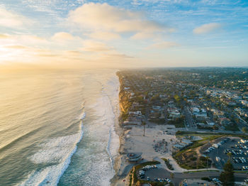 Aerial view of sea and buildings against sky during sunset