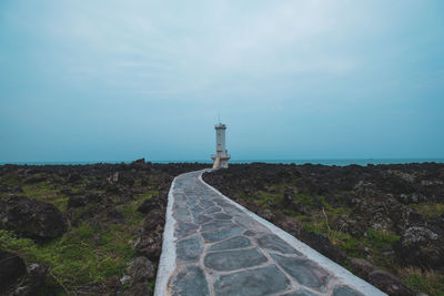 Lighthouse against beach and sky