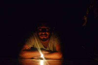 Portrait of young man by lit diya in darkroom