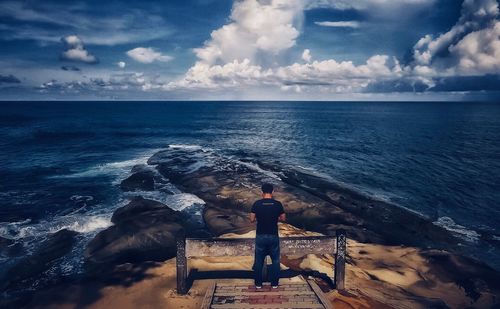 Rear view of man looking at sea against sky