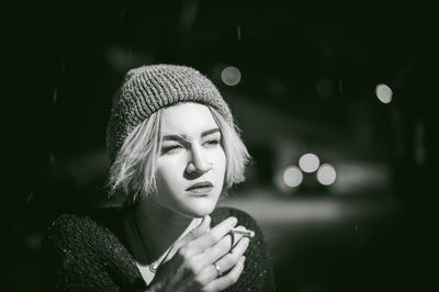 Close-up of young woman smoking cigarette at night