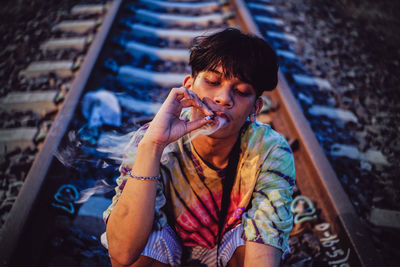 Young man smoking on railroad track