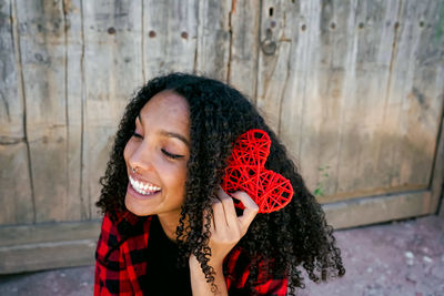 Smiling young woman holding heart shape