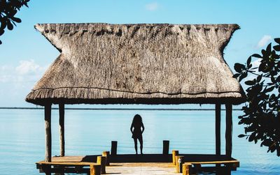Rear view of silhouette woman standing in gazebo on pier over sea