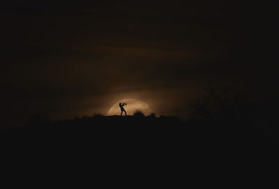 Silhouette of person on landscape against sunset sky