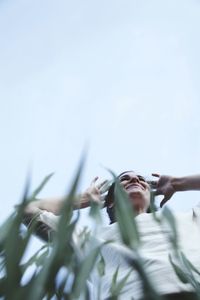 Low angle view of hand on plant against sky