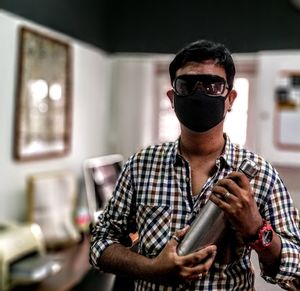 Portrait of young man holding sunglasses