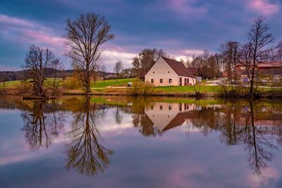 Reflection of trees and buildings on lake against sky