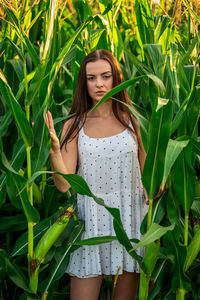 Portrait of young woman standing amidst plants