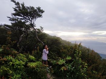 Man standing by tree against sky