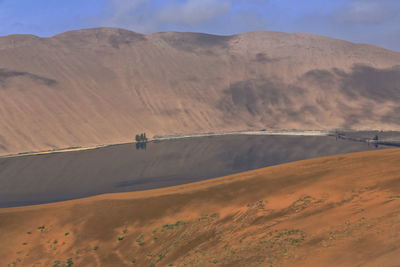 1158 sumu barun jaran lake in badain jaran desert-dark water reflecting cloudy sky and dunes. china.