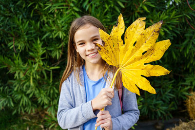 Portrait of a smiling girl holding yellow plant