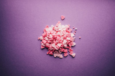 Close-up of pink heart shape candies on purple background