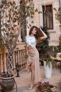 Side view of young woman standing by plants
