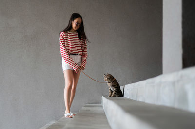 Portrait of young woman standing against wall