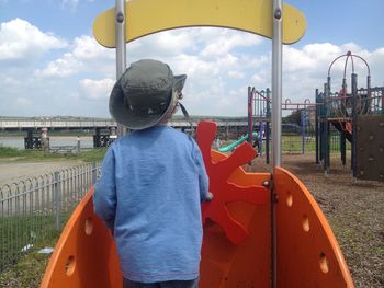 Boy on umbrella against sky