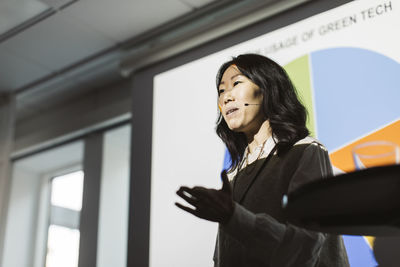 Female entrepreneur gesturing while giving presentation during event at convention center
