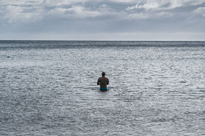 Rear view of man in sea against sky