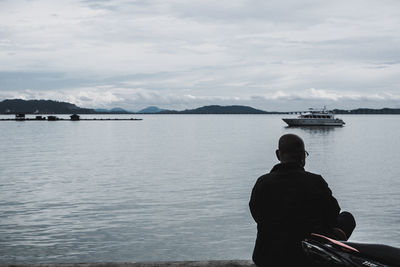 Rear view of man looking at sea against sky