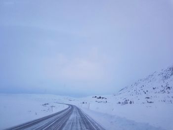 Scenic view of snow covered road against sky