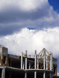 Low angle view of incomplete building against cloudy sky