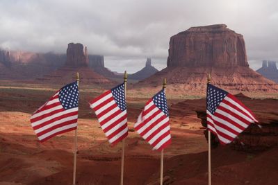 American flags by rock formations against cloudy sky