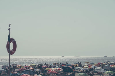 Crowd on beach against clear sky