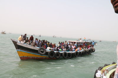 People on boats in sea against clear sky