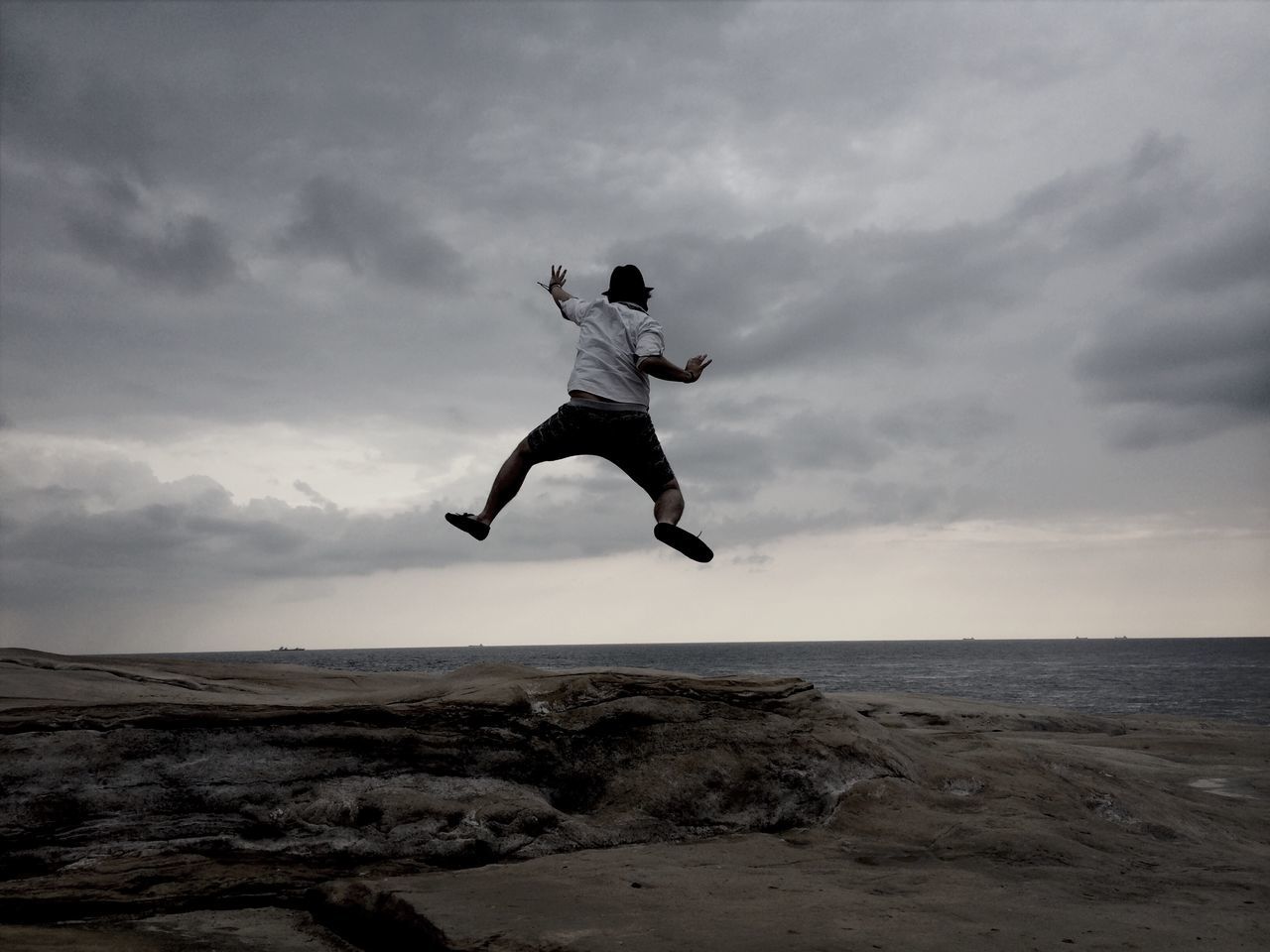 full length, jumping, mid-air, leisure activity, lifestyles, sky, freedom, arms outstretched, fun, enjoyment, cloud - sky, vitality, sea, extreme sports, carefree, beach, vacations, balance