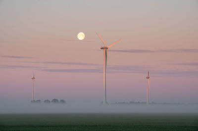 Wind turbines on fields with the moon in the background