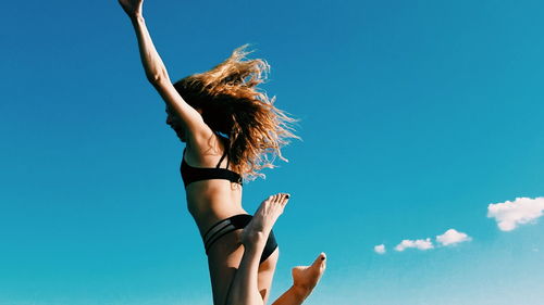 View of young woman jumping against blue sky