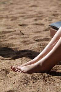 Low section of woman relaxing on sand at beach