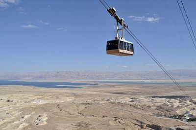 Overhead cable car on landscape against sky