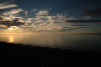 Scenic view of sea against cloudy sky during sunrise