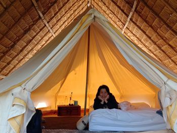 Portrait of smiling young woman standing against illuminated building