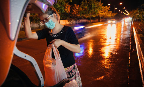 Woman holding umbrella on illuminated street at night