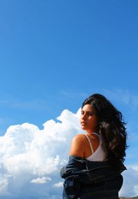 Low angle view of woman standing against blue sky